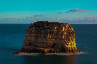 Rock formation in sea against sky