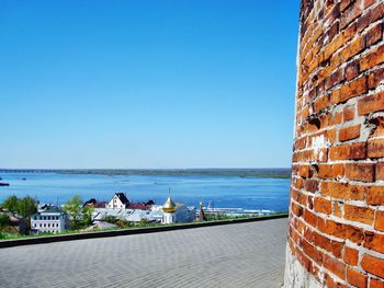 Sea by cityscape against clear blue sky