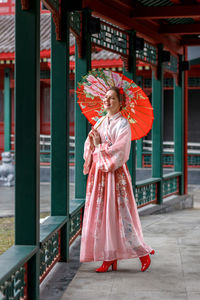 Rear view of woman with umbrella standing in city