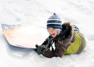 Portrait of boy with sled playing on snowy field