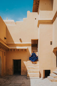 Rear view of woman moving up on steps of building