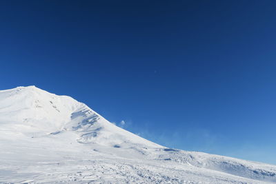 Scenic view of snowcapped mountains against clear blue sky