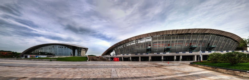 View of footpath in city against cloudy sky