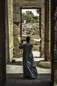 Rear view of man photographing ruined temple