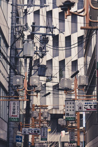 Low angle view of lighting equipment and cables against building