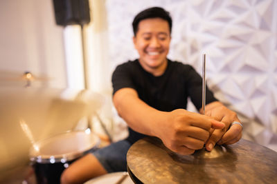 Portrait of young man playing drum at home