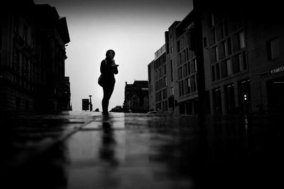 Side view of silhouette man standing on street against buildings