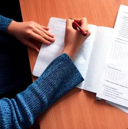 High angle view of woman writing in book on desk at home