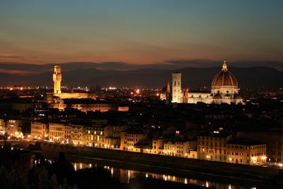 Illuminated buildings in city against sky at night