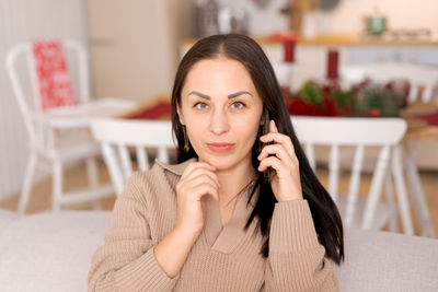 Happy woman sits on couch holding cell phone, using cellular technology