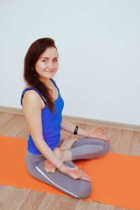 Portrait of young woman sitting on wall at home