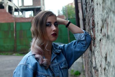Portrait of beautiful woman with make-up standing by brick wall
