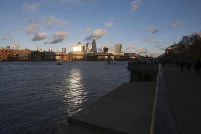 City buildings by river against sky