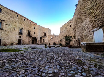 Street amidst buildings against clear blue sky