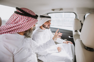 Men holding mobile phone while sitting in bus