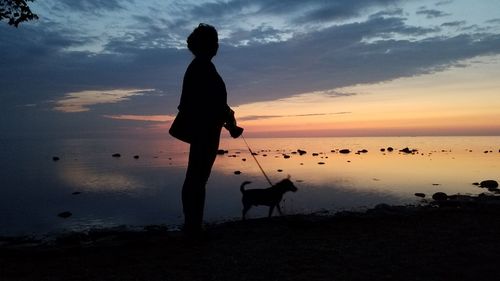 Silhouette man standing on beach against sky during sunset