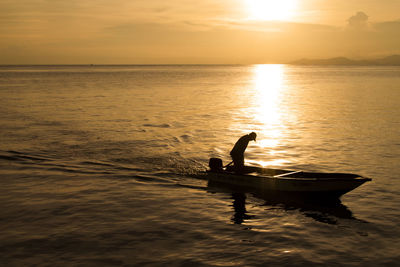 Silhouette boat in sea against sky during sunset