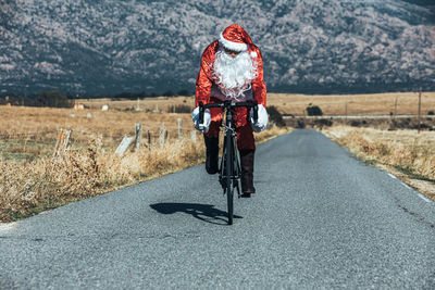 Rear view of man riding bicycle on road