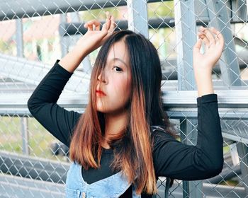 Portrait of young woman looking away while sitting on fence