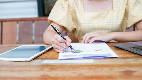 Midsection of woman using mobile phone on table