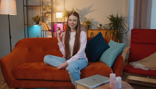 Portrait of young woman sitting on sofa at home