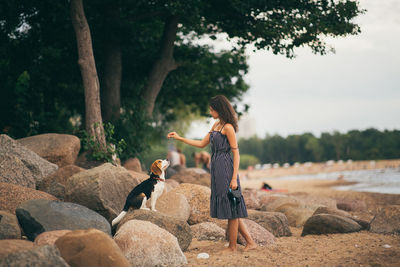 Side view of woman on rock against trees