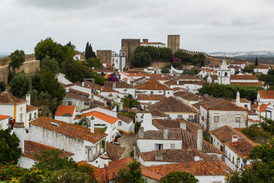 High angle view of houses in medieval town of obidos with castle against sky