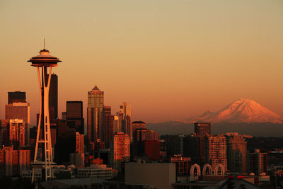 Space needle tower in city by mountain against clear sky during sunset