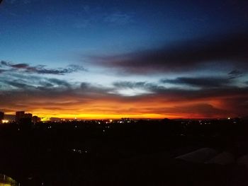 Silhouette cityscape against dramatic sky during sunset