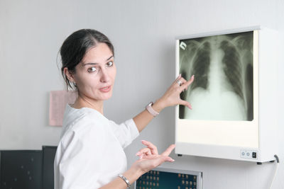 Woman radiologist pointing to the screen with x-ray image of lungs and talking or discussing case