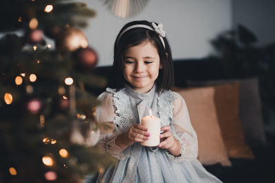 Cute girl holding candle sitting on chair