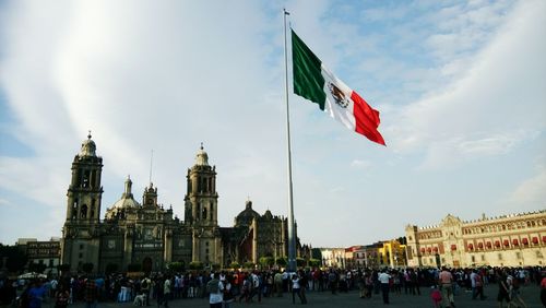 People at town square against sky in city