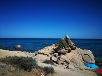 Rocks on beach against clear blue sky