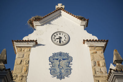Low angle view of crucifix painting by church against clear blue sky