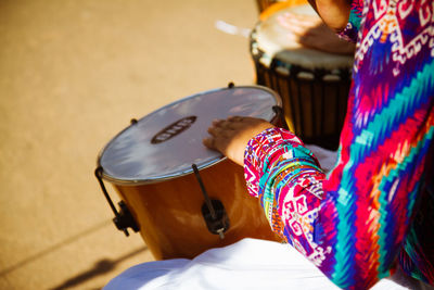 Woman playing drums in a sunny day.