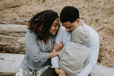 High angle view of couple with son sitting on log in forest