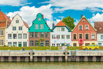 Bridge over river by buildings against sky