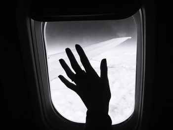 Silhouette of woman against sky seen through airplane window