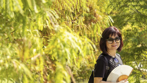 Portrait of young woman standing against plants