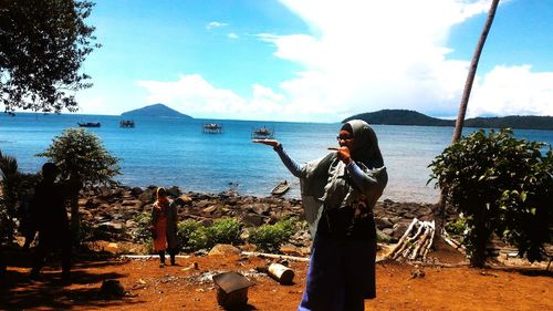 Woman standing by sea against sky