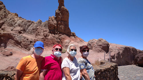 Group of people on rock against clear sky