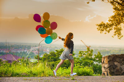 Full length of woman standing on field against sky during sunset