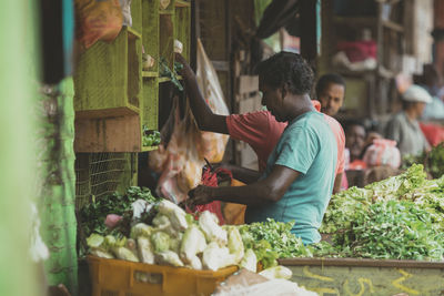 Man and vegetables for sale in market