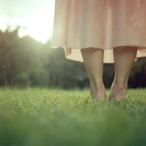 Low section of woman standing on grassy field