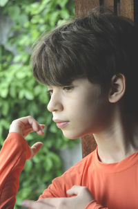 Portrait of a boy at the window wearing orange shirt. 