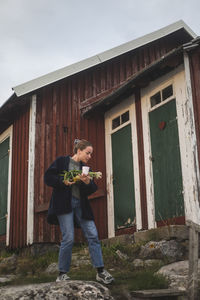 Woman with scallion walking by cottage