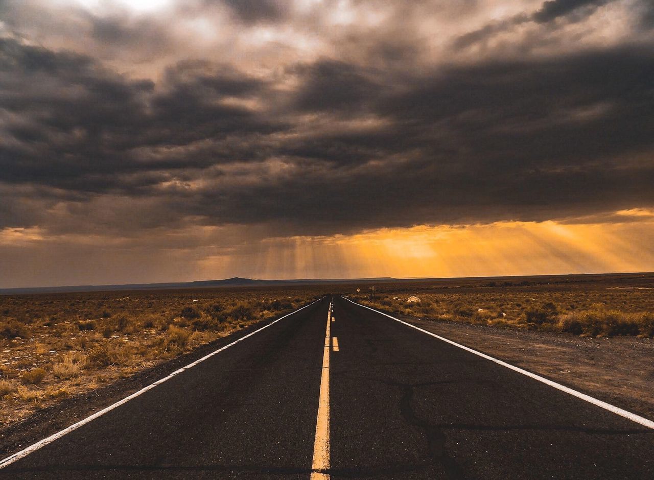 horizon, cloud, road, sky, transportation, sign, environment, nature, landscape, the way forward, morning, vanishing point, symbol, dramatic sky, road marking, sunlight, no people, marking, dusk, beauty in nature, highway, diminishing perspective, horizon over land, scenics - nature, travel, land, cloudscape, outdoors, storm, street, sunrise, moody sky, asphalt, urban skyline, travel destinations, city, prairie, rural scene, dividing line, tranquility, storm cloud, remote, plain, field