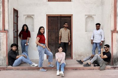 Full length portrait of friends standing against wall