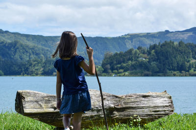 Rear view of girl standing by lake against mountain