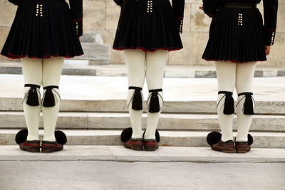 Low section of women wearing uniforms while standing on footpath